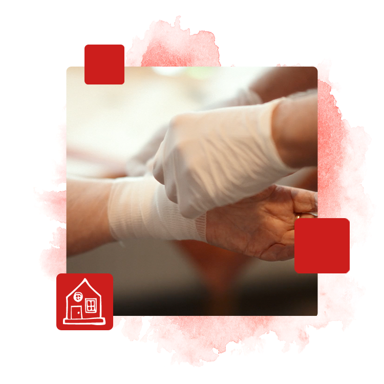 Eine Handgelenk wird verbunden. Der Pfleger trägt Schutzhandschuhe.